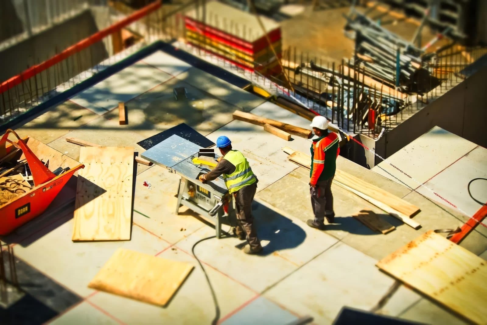 Construction workers cutting lumber on a building site, the kind of job where workers compensation claims arise