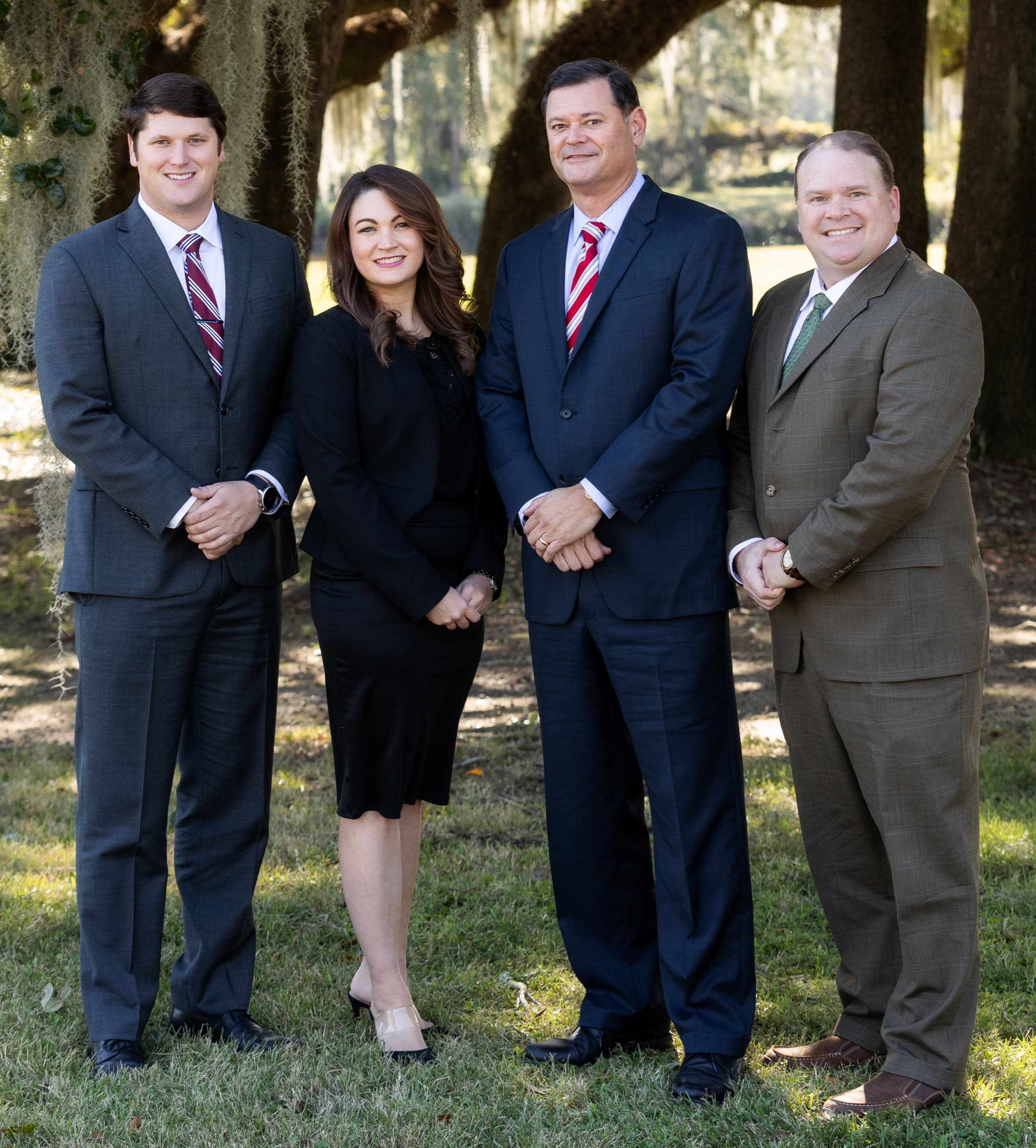 Rick Tadda, Sarah Tormey, Erik Tadda, and Jeremy Hader of The Tadda Law Firm standing together under live oaks